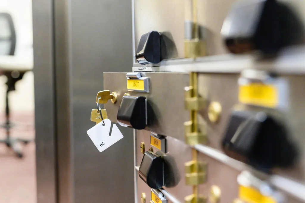 A safe deposit box door standing open with the key and tag still in the lock